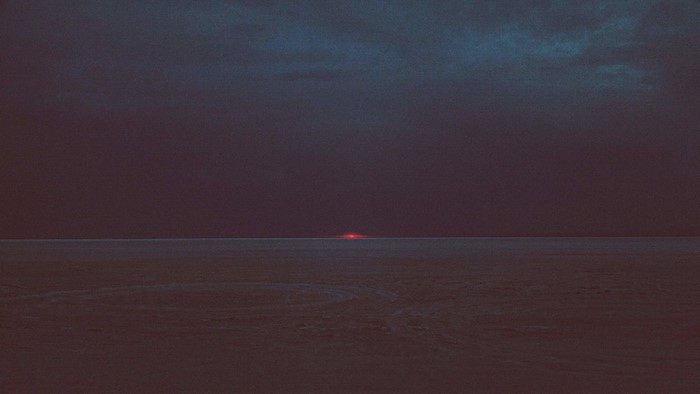 Dark landscape with a faint red glow on the horizon