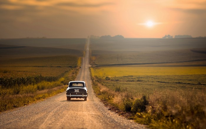 Car driving on a dirt road at sunset