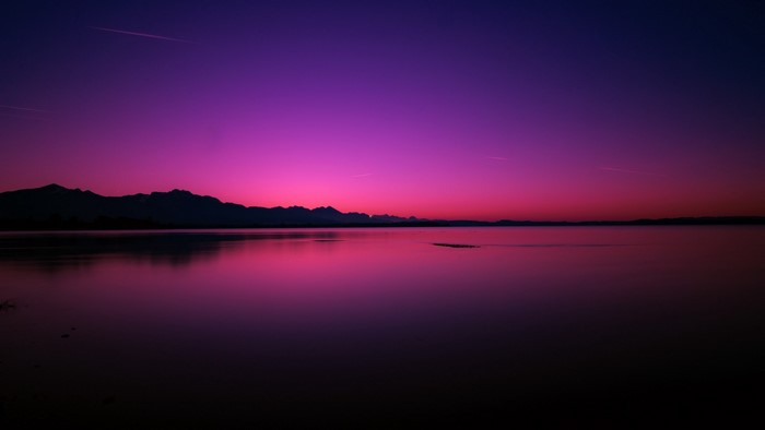 Purple and pink sunset over a lake and mountains