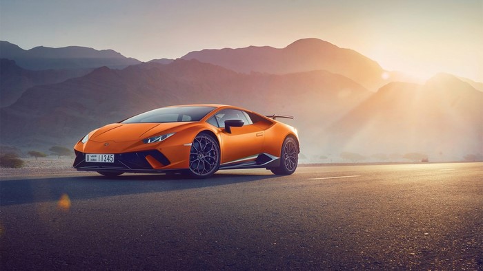 Orange Lamborghini Huracan on a road at sunset
