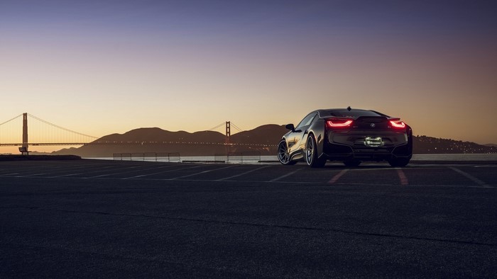 BMW i8 parked with Golden Gate Bridge at sunset