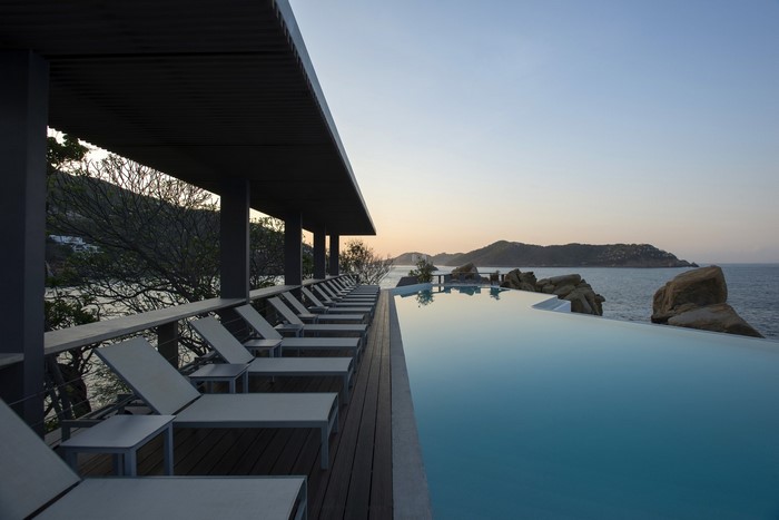 Resort infinity pool and deck chairs overlooking the sea and islands