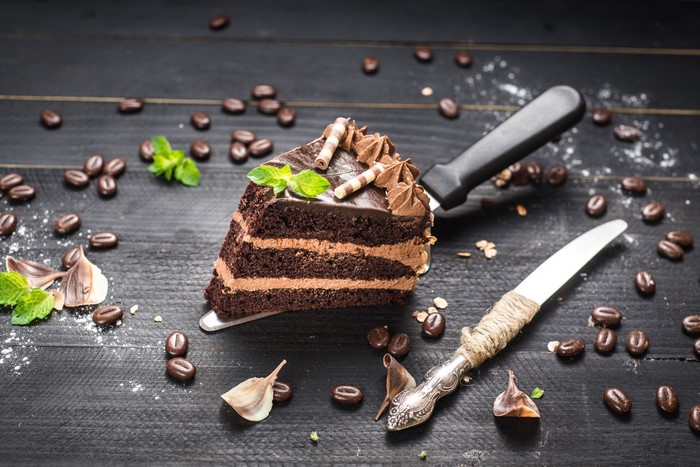 Slice of chocolate cake with coffee beans and mint leaves