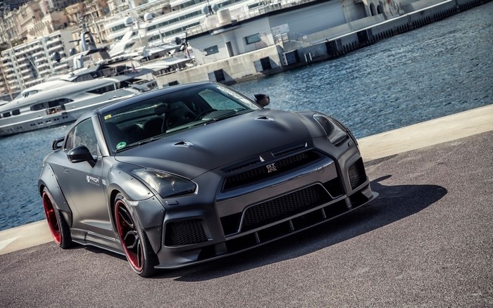 Matte black Nissan GT-R with red accents by the water