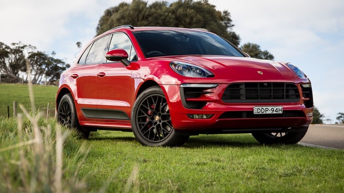 Red Porsche Macan parked on grassy hill
