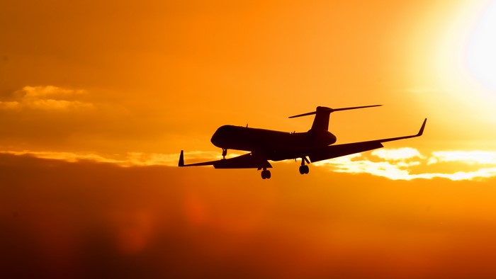 Silhouette of a Gulfstream airplane against an orange sunset sky