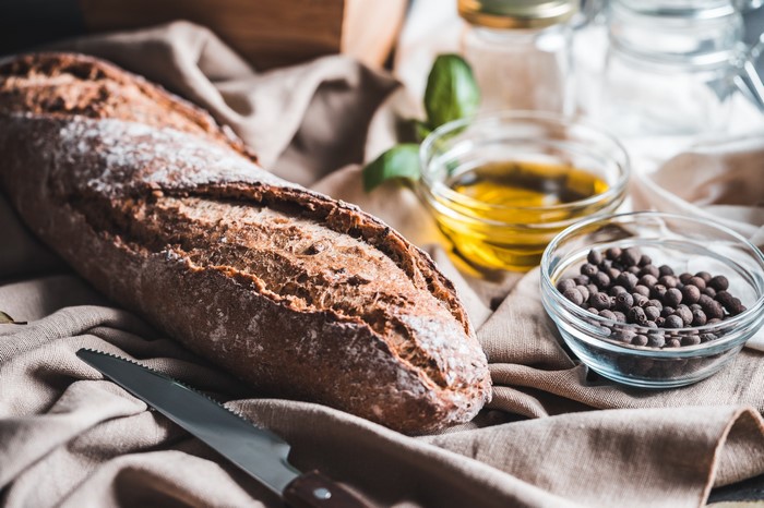 Still life with baguette, olive oil, and peppercorns