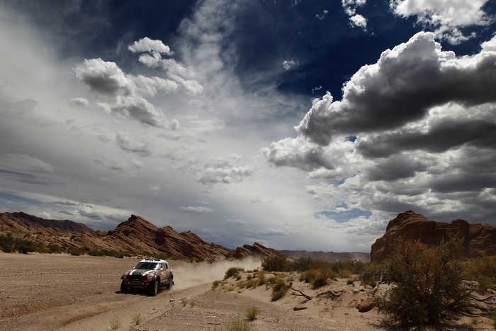 Rally car driving through a desert landscape