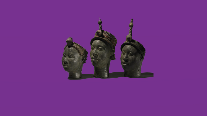 Three bronze heads from Nigeria on a purple background