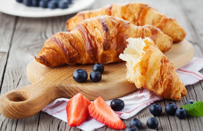Croissants with blueberries and strawberries on a cutting board