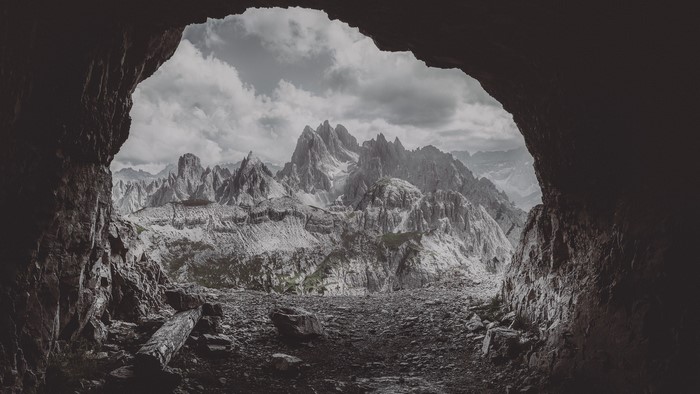 View of jagged mountains from a dark cave entrance