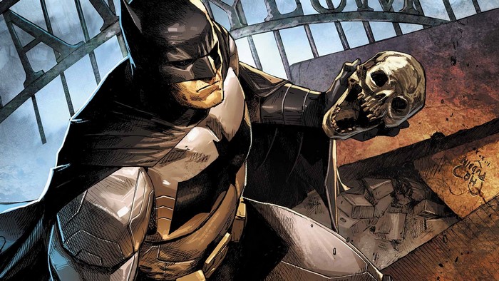 Batman holding a skull in front of a metal structure