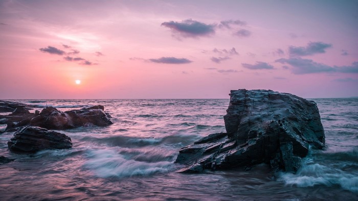 Ocean waves crashing on rocks at sunset