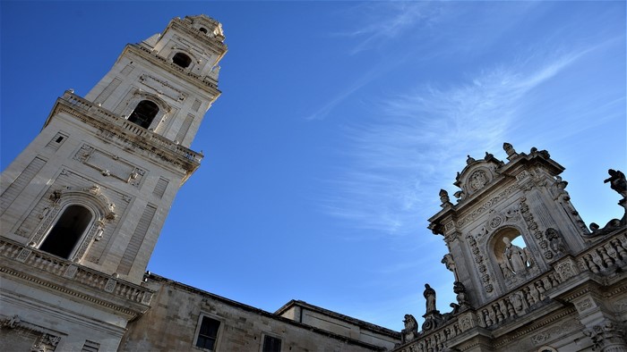 Cathedral tower and facade against blue sky in Italy