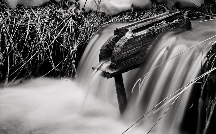 Monochrome long exposure of water flowing over wood