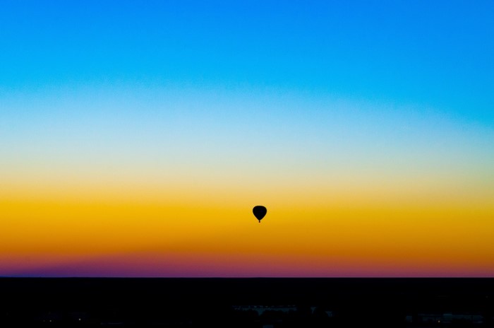 Hot air balloon silhouetted against a sunset sky