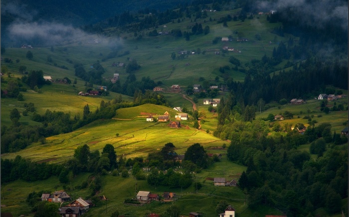 Village nestled in a green mountain valley with mist
