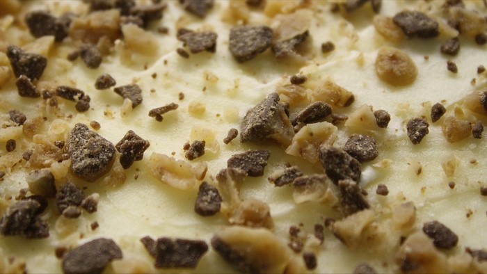 Close-up of white frosting with chocolate and toffee pieces