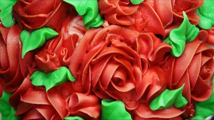 Red roses and green leaves frosting on a cake