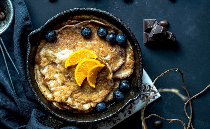 Pancakes with blueberries and orange slices in a cast iron skillet