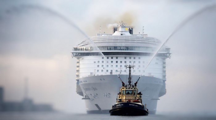 Tugboat sprays water on a large cruise ship