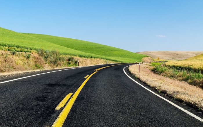 Curving asphalt road through rolling green hills