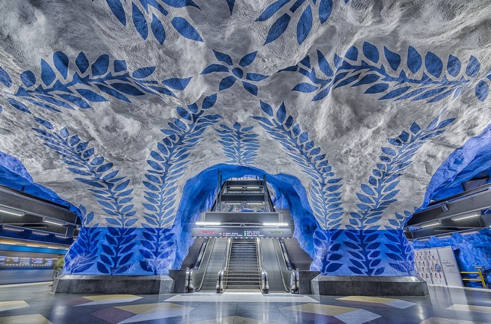 Stockholm Metro station with blue leaf art and escalators