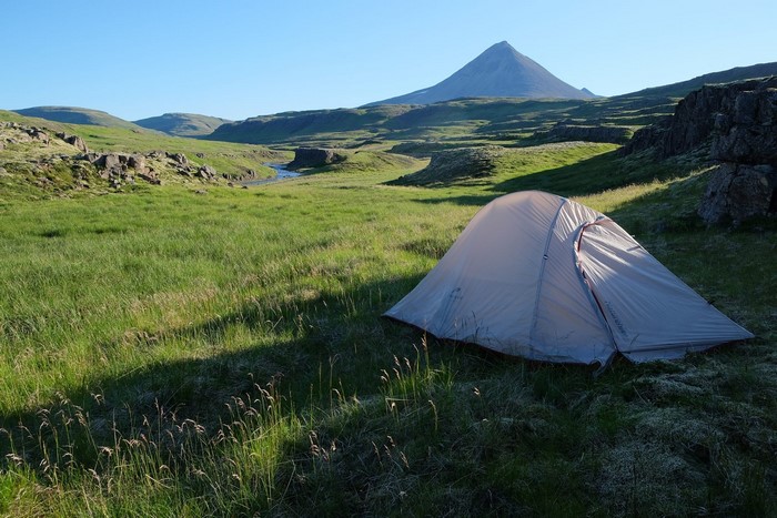 Tent in a green valley with a mountain in Iceland