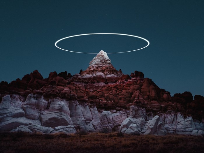 Rock formations under a starry sky with a light ring