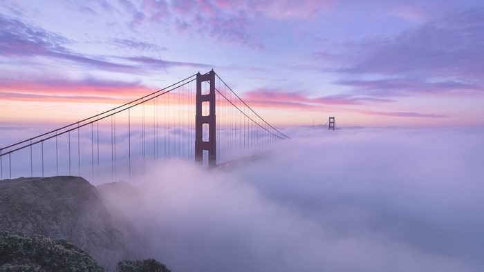 Golden Gate Bridge shrouded in fog at sunrise