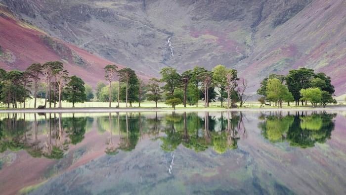 Trees reflected in a lake with mountains in the background