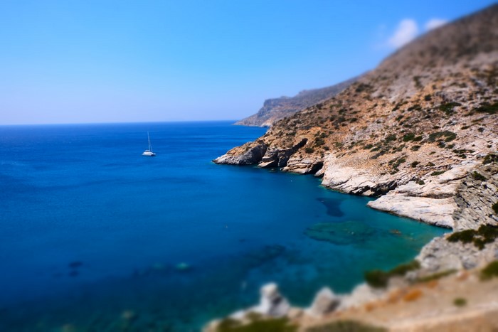 Sailboat in the Aegean Sea near a rocky coast in Greece