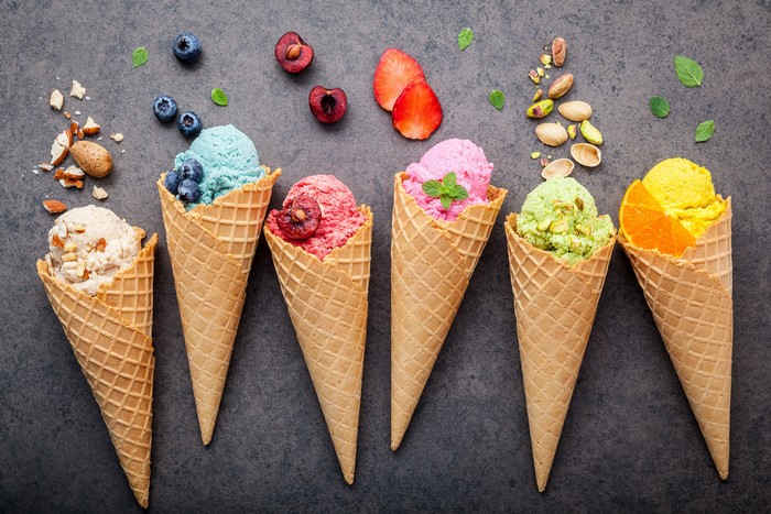 Colorful ice cream cones with fruits and nuts, top view