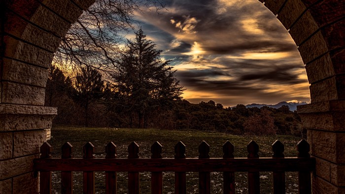 Archway overlooking sunset over hills and trees