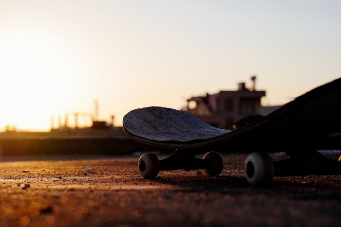 Skateboard on pavement at sunset