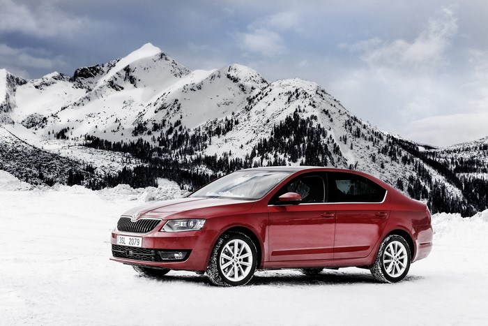Red Skoda car in snowy mountains