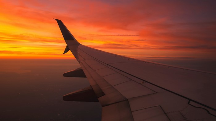 Airplane wing against a vibrant sunset sky