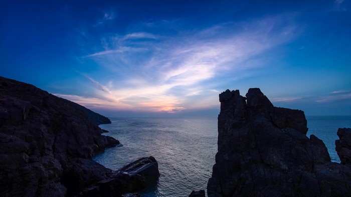 Rocky coastline at sunset with ocean and sky