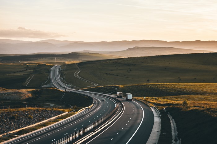 Highway landscape with trucks and hills at sunset