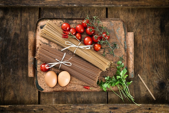 Pasta, tomatoes, eggs, and parsley on a tray