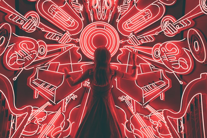 Woman conducting a neon orchestra of instruments