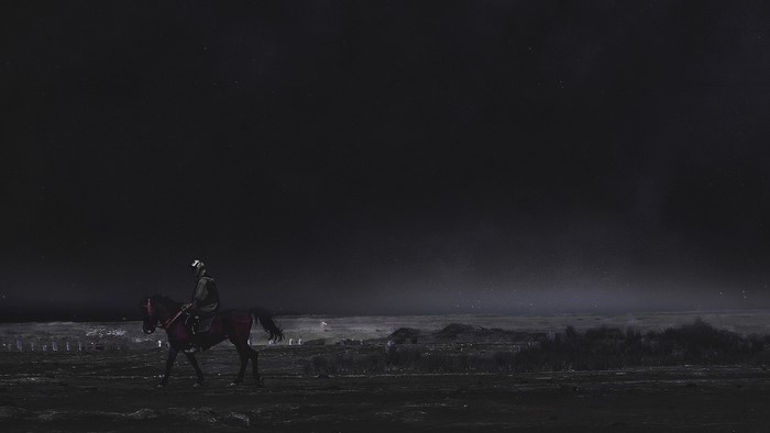 Man riding a horse in a dark desert landscape