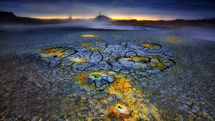 Cracked dry ground with yellow and green mineral deposits