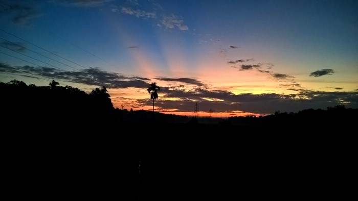 Sunset with sun rays over a silhouetted landscape