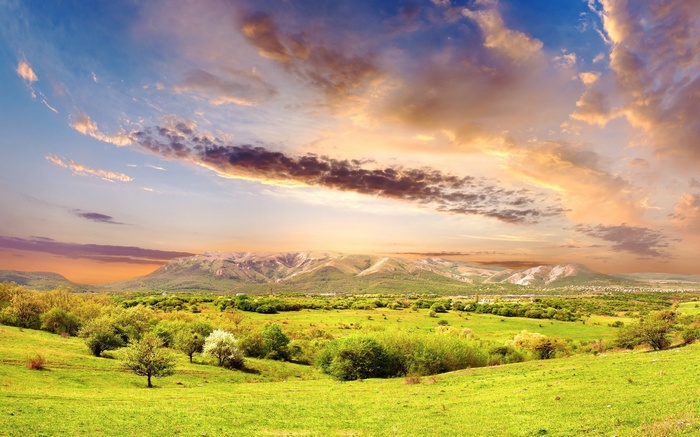 Green rolling hills and mountains under a dramatic sky