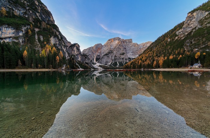 Mountains reflecting in a calm lake with trees and a small building