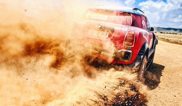 Red Mini Cooper rally car kicking up dust