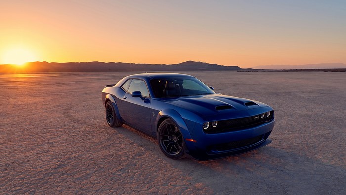 Blue Dodge Challenger in a desert at sunset