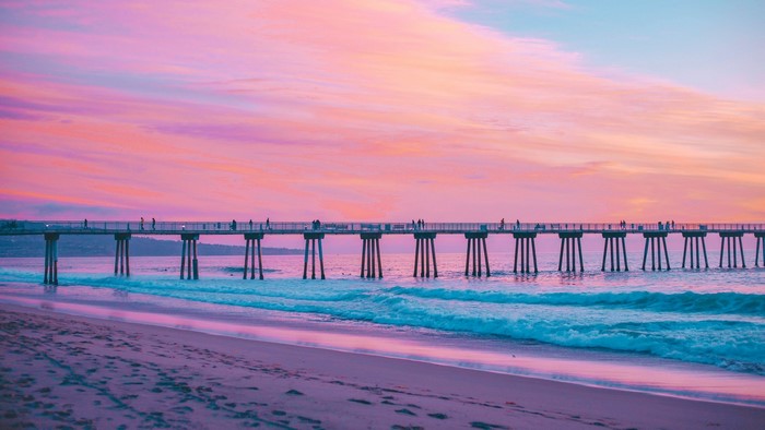 Pier over the ocean at sunset with pink sky