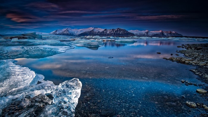 Icebergs and snow-capped mountains reflected in water